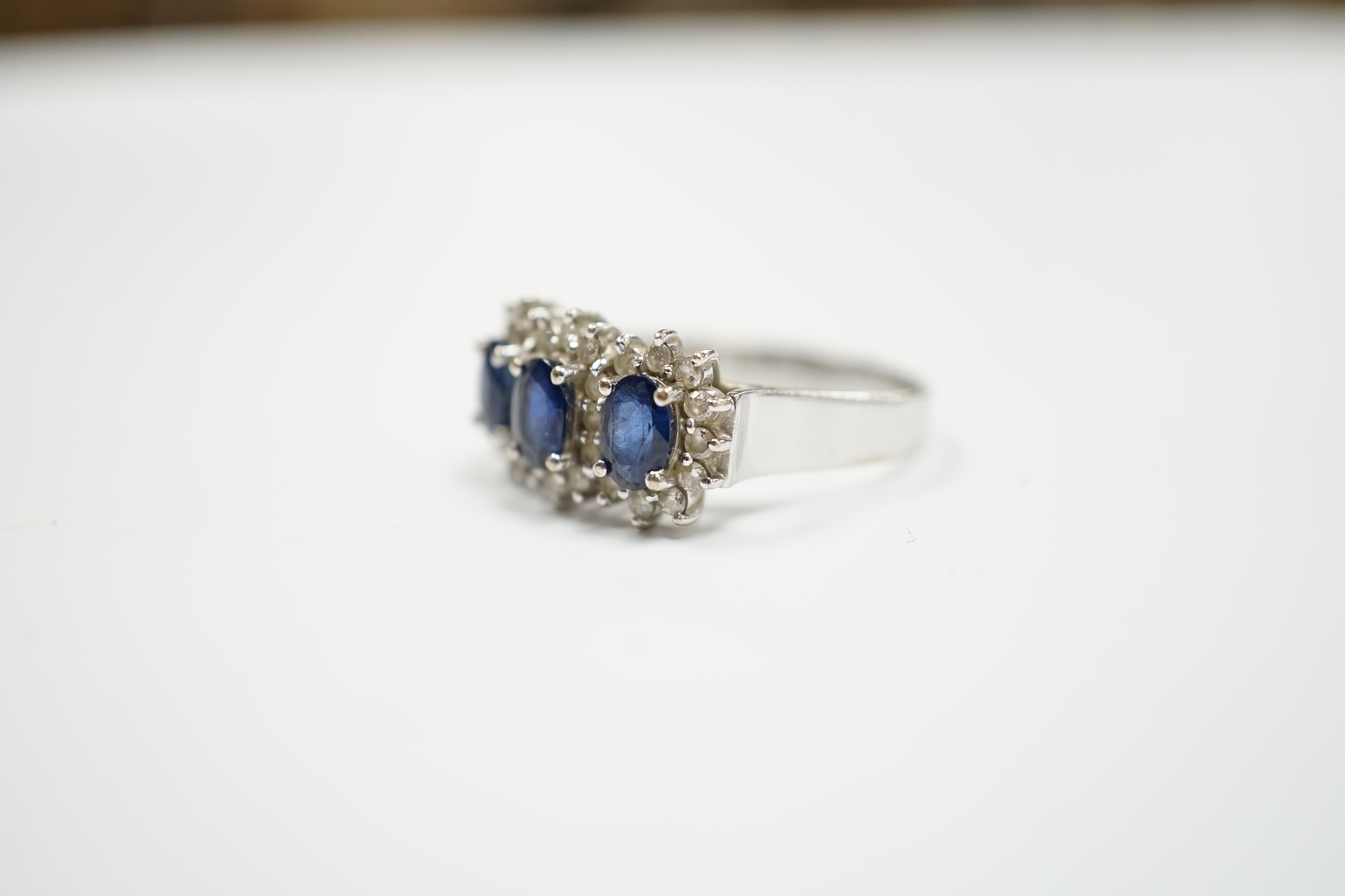 An 18k white metal, sapphire and diamond set triple cluster ring, size Q. gross weight 5.8 grams.